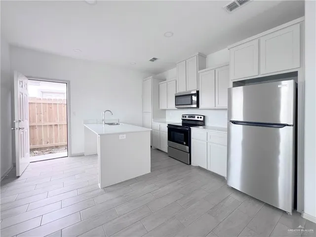 a kitchen with a refrigerator sink and white cabinets
