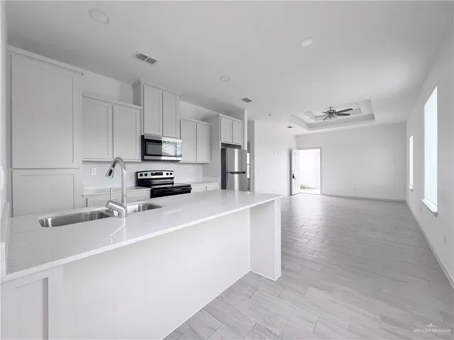 a kitchen with stainless steel appliances a sink a stove a microwave a sink a refrigerator and cabinets