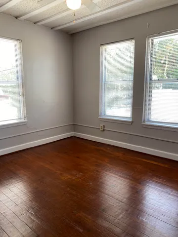 an empty room with wooden floor and windows