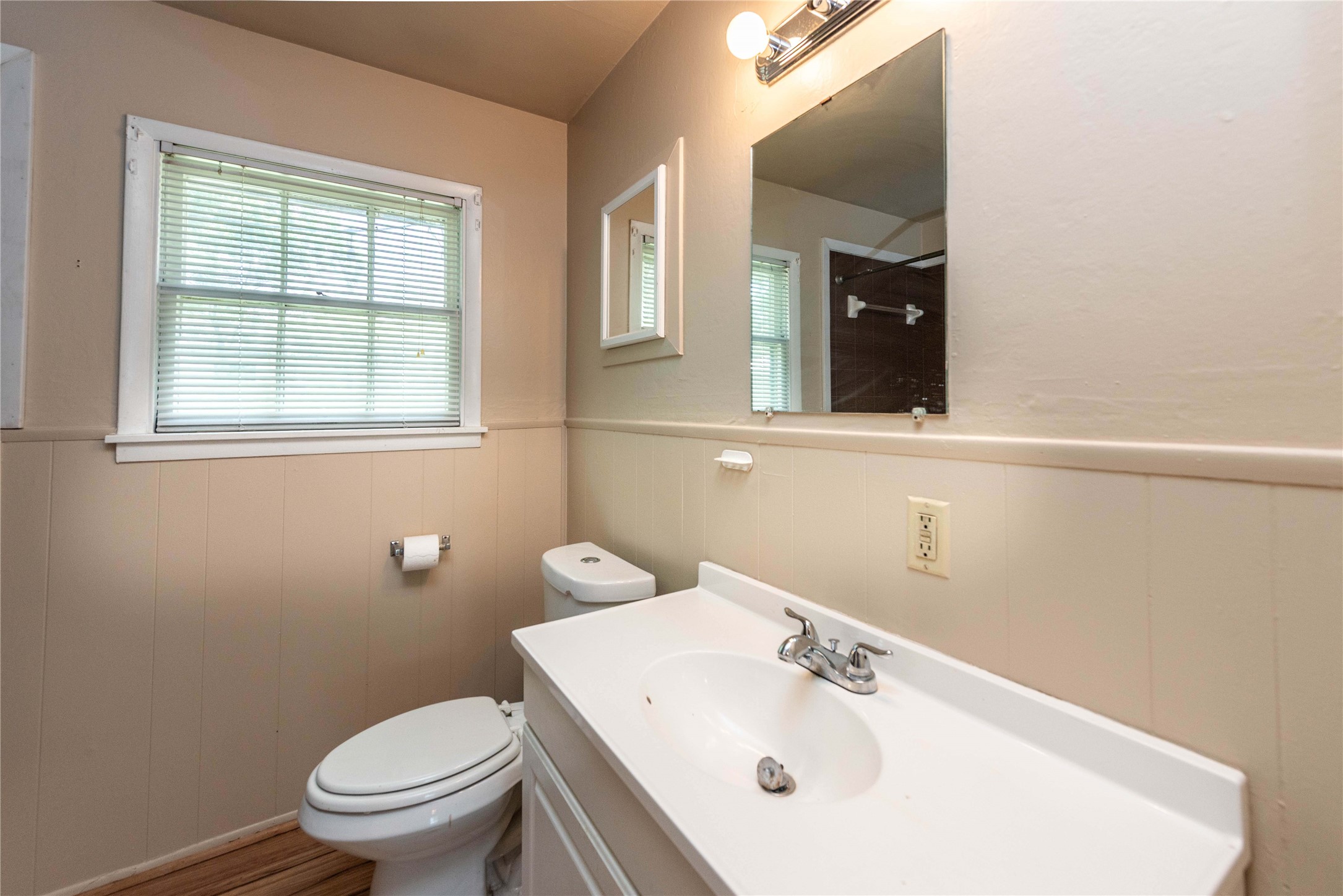 7602 Delafield Lane Austin, TX 78752 - Photo 8 of 17 A well-maintained bathroom with wood paneling and a large mirror above the vanity.