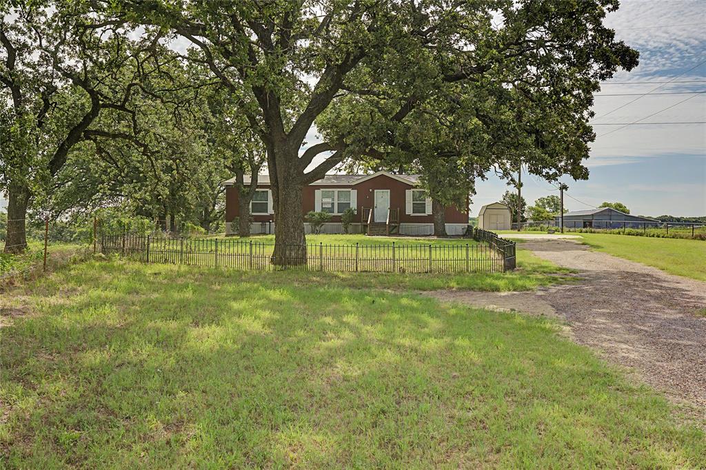 177 New Highland Road Springtown, TX 76082 - Photo 37 of 40 Red exterior residence featuring a white front door, white window trim, and a fenced front yard