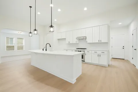 a kitchen with stainless steel appliances sink a stove and white cabinets