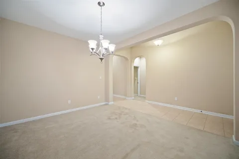 a view of an empty room with a chandelier fan