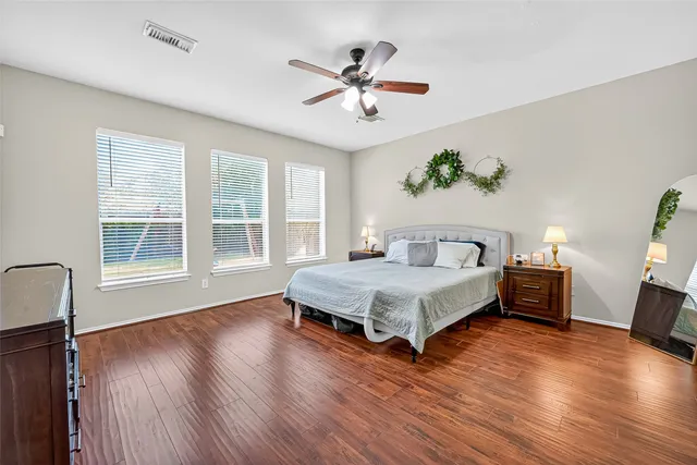 a spacious bedroom with a bed and wooden floor