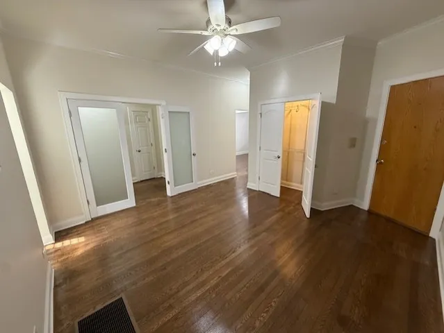 an empty room with wooden floor and a ceiling fan