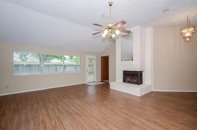 an empty room with wooden floor fan and windows
