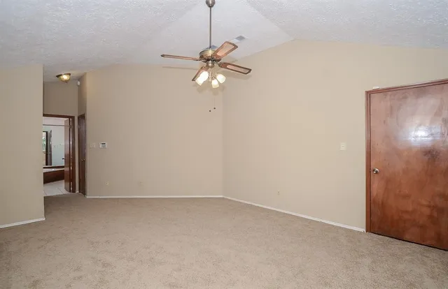 an empty room with a chandelier fan and windows