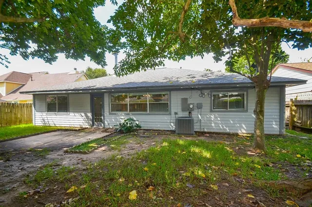 a view of a backyard with large trees and wooden fence