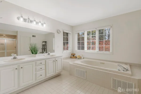a spacious bathroom with double vanity a window a bathtub and double vanity