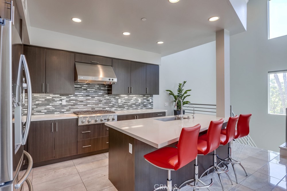 59 Gramercy Irvine, CA 92612 - Photo 21 of 71 a kitchen with stainless steel appliances kitchen island granite countertop a table chairs in it and wooden floors