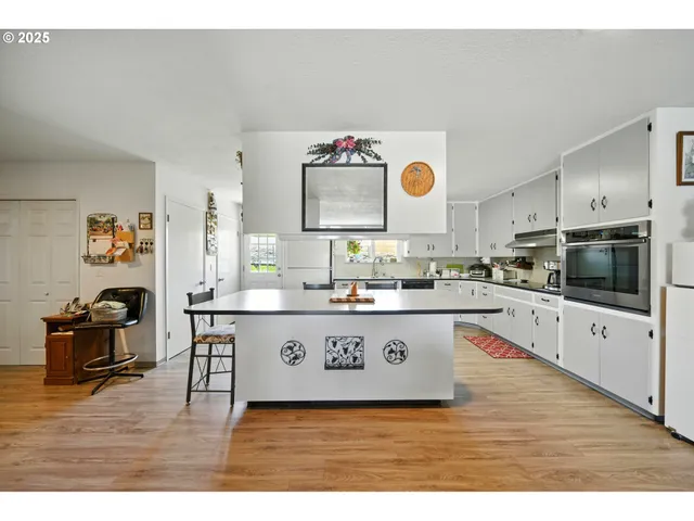 a kitchen with stainless steel appliances granite countertop a sink cabinets and wooden floor