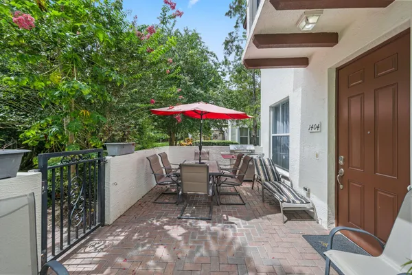 a view of a patio with a table and chairs under an umbrella with a small yard