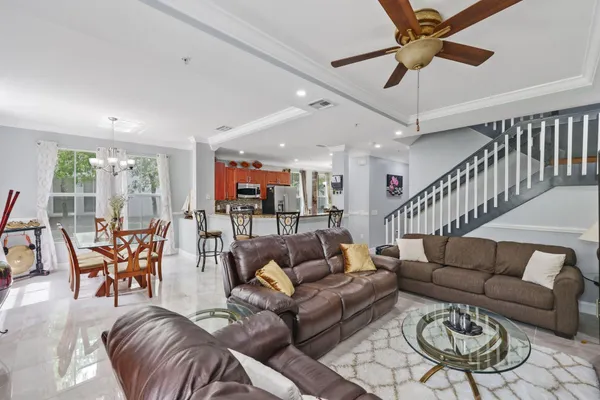 a living room with furniture kitchen view and a wooden floor
