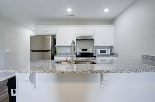 a kitchen with stainless steel appliances granite countertop a sink a stove and a refrigerator