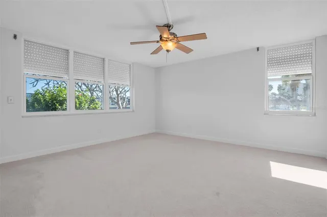 an empty room with windows and fan