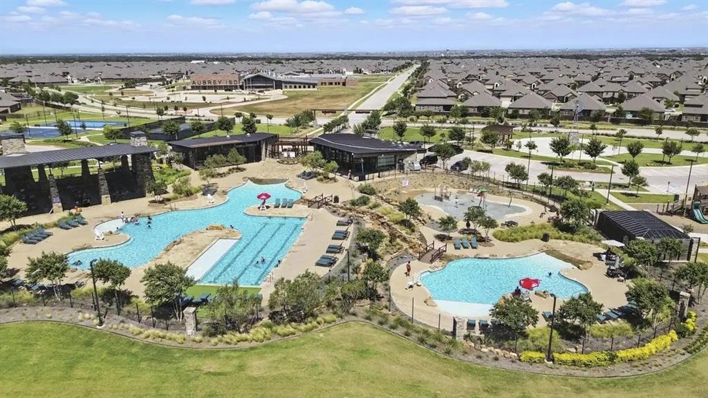 9828 Quail Pointe Road Aubrey, TX 76227 - Photo 3 of 23 Community amenity center featuring multiple pools, a water play area, covered structures, and surrounding green spaces