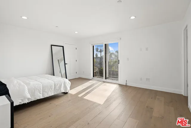 a spacious bedroom with a bed and wooden floor