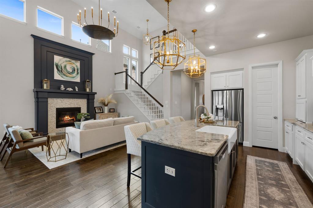 1806 Evening Star Road Frisco, TX 75033 - Photo 4 of 38 Kitchen with dark wood-type flooring, a breakfast bar area, pendant lighting, a kitchen island with sink, and white cabinets