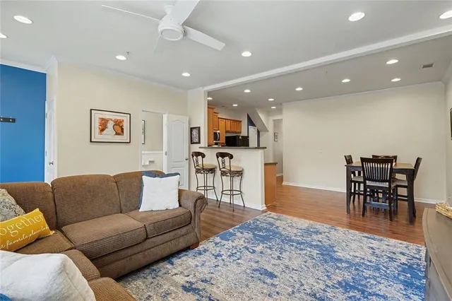 a living room with furniture wooden floor and a kitchen