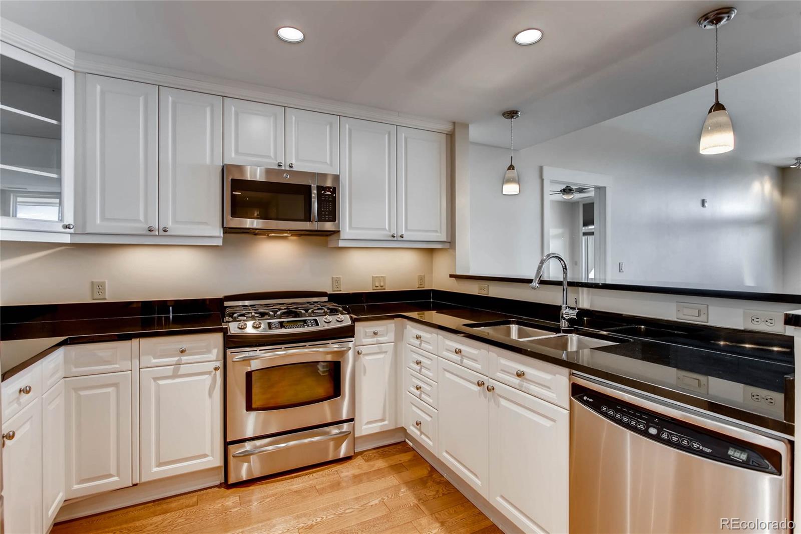 7220 W. Bonfils Lane, Unit 410 Lakewood, CO 80226 - Photo 11 of 27 a kitchen with granite countertop a stove a microwave a sink and cabinets
