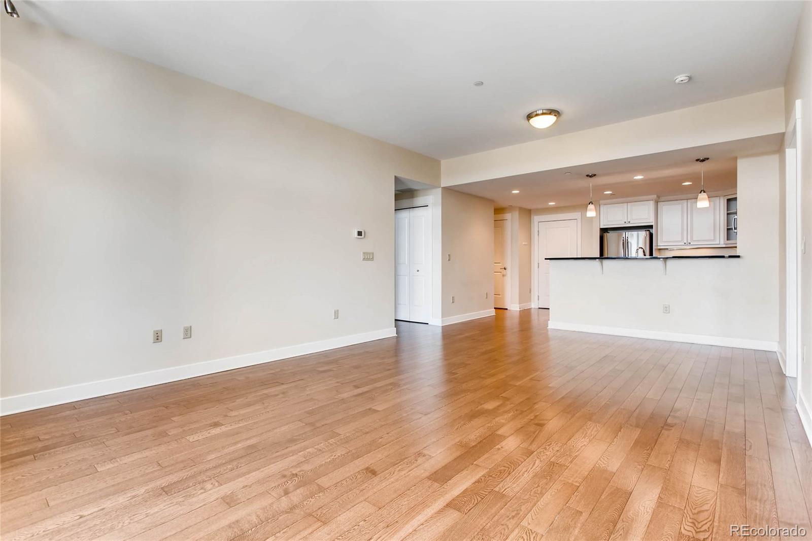 7220 W. Bonfils Lane, Unit 410 Lakewood, CO 80226 - Photo 8 of 27 an empty room with wooden floor and kitchen view