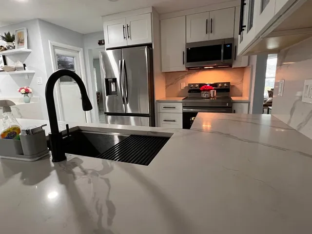 a kitchen with stainless steel appliances a sink a stove a microwave a refrigerator and cabinets