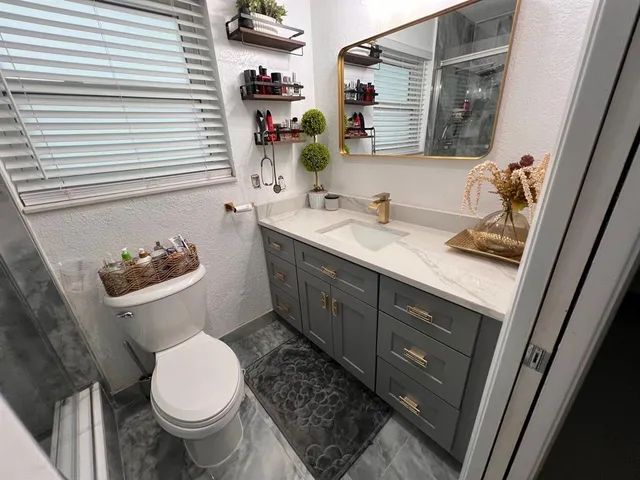 a bathroom with a granite countertop sink toilet and shower