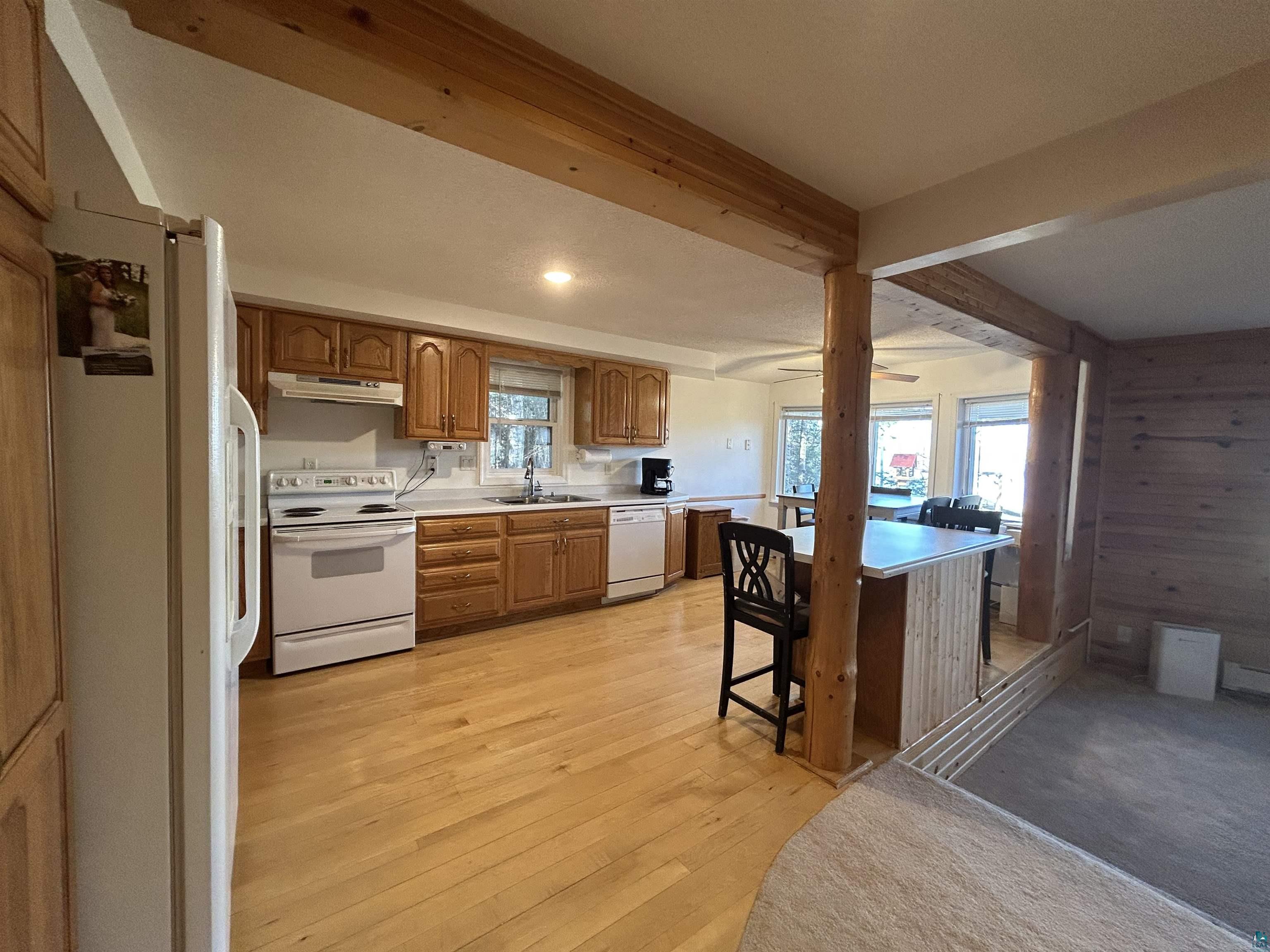 8655 South Lyman Lake Road South Range, WI 54874 - Photo 53 of 64 Kitchen featuring wood finish cabinets, white appliances, light countertops, wood walls, and a breakfast bar