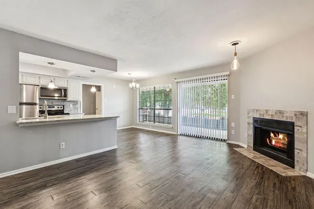 a living room with stainless steel appliances wooden floor and a fireplace