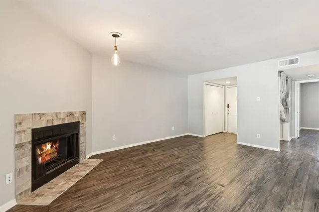 a view of an empty room with wooden floor fireplace and a window