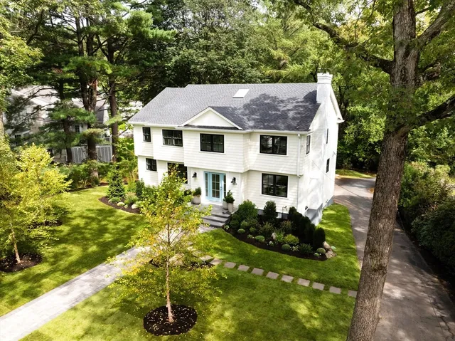 a view of a house with a small yard plants and large tree