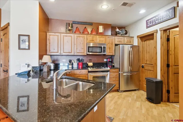 a kitchen with stainless steel appliances granite countertop a refrigerator a stove and a sink