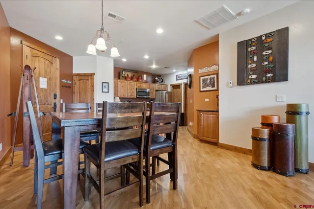 a dining room with stainless steel appliances kitchen island granite countertop a refrigerator a stove a microwave oven a dining table and chairs with wooden floor