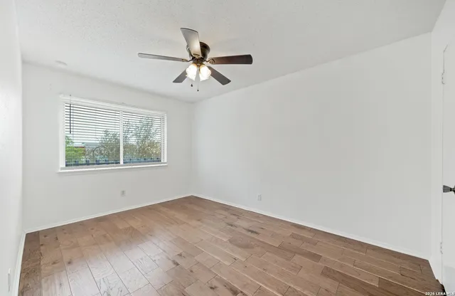 a view of empty room with wooden floor and fan