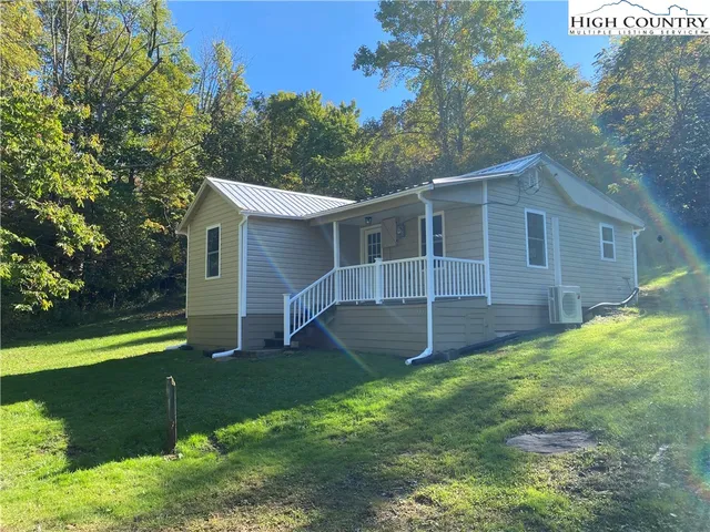 a view of a yard in front of a house with plants and large tree