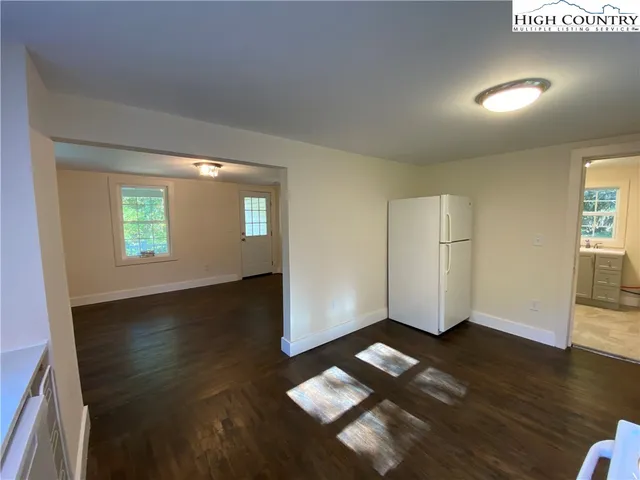 an empty room with wooden floor cabinet and windows
