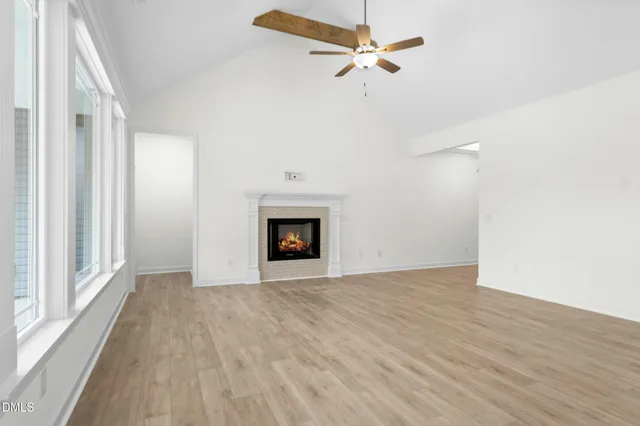a view of an empty room with wooden floor fireplace and a window