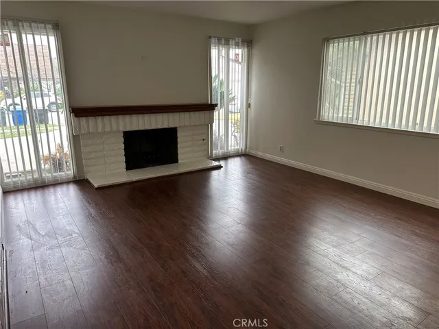 an empty room with wooden floor fireplace and windows
