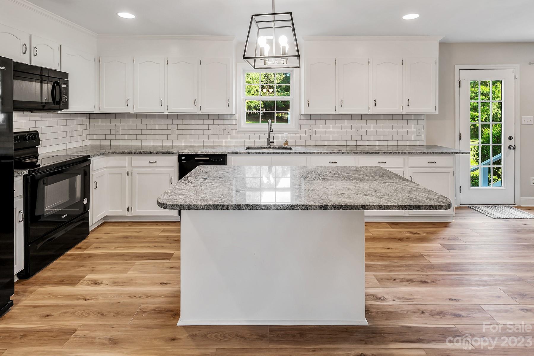 211 Todd Circle Wingate, NC 28174 - Photo 13 of 45 a kitchen with kitchen island granite countertop a stove a sink and a granite counter tops with wooden floors