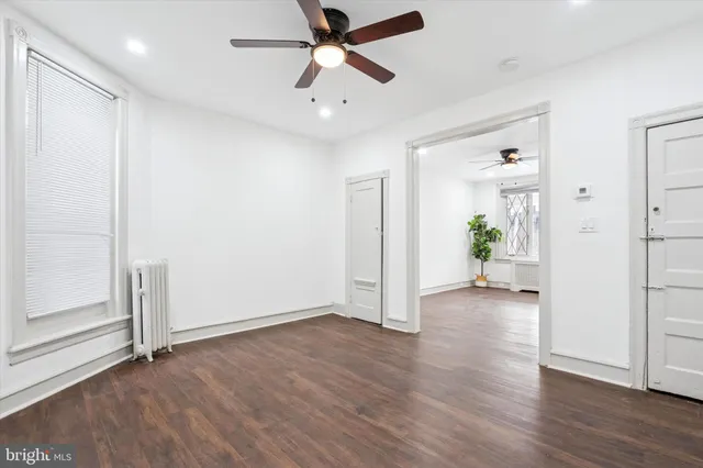 an empty room with wooden floor and a ceiling fan