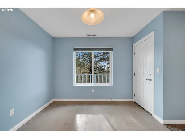 a view of an empty room with a window and wooden floor