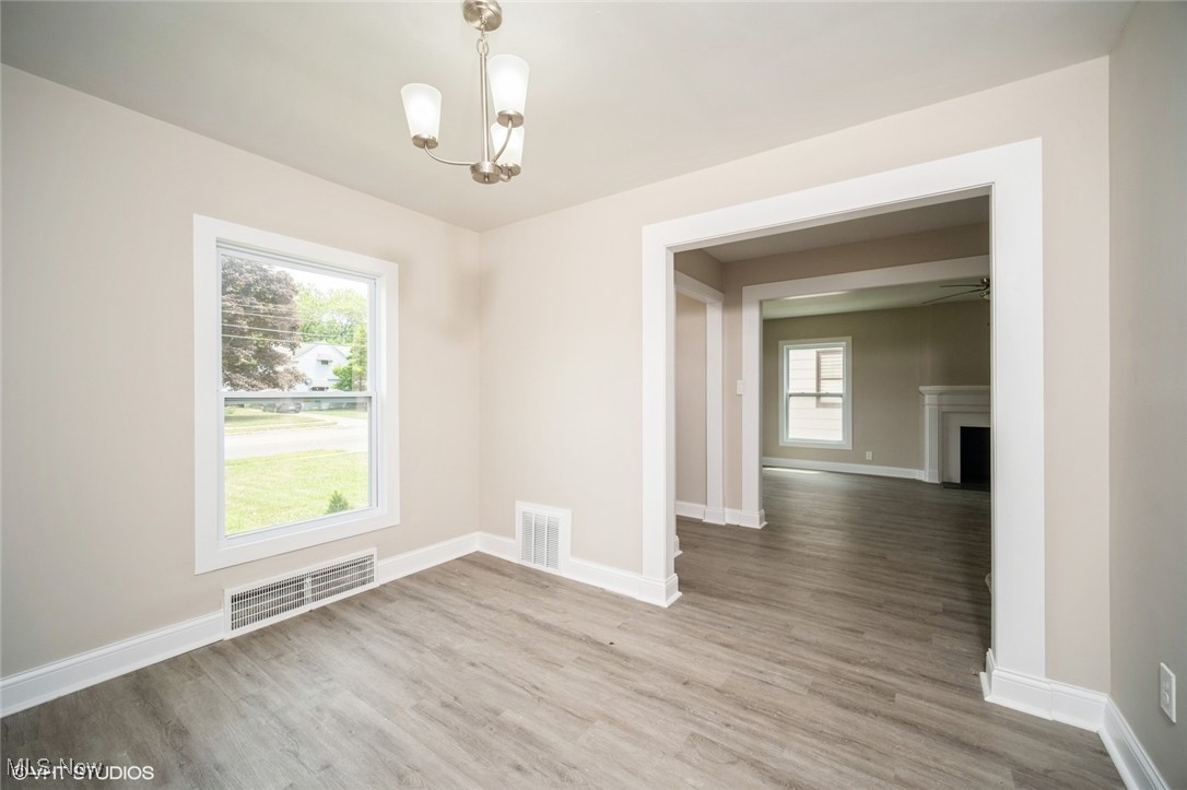 2188 North Taylor Road Cleveland Heights, OH 44112 - Photo 5 of 15 Unfurnished dining area featuring a chandelier, wood finished floors, a fireplace, and a ceiling fan