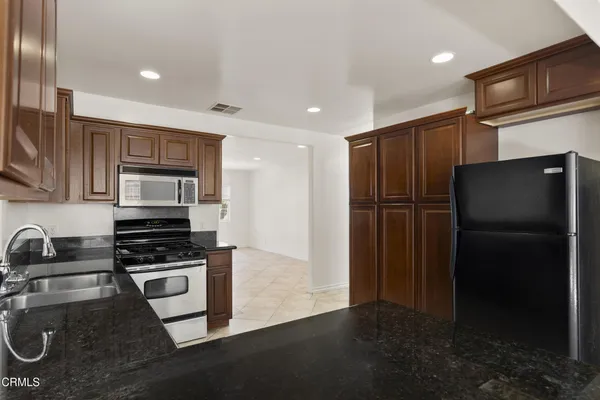 a kitchen with stainless steel appliances granite countertop a refrigerator and a stove top oven