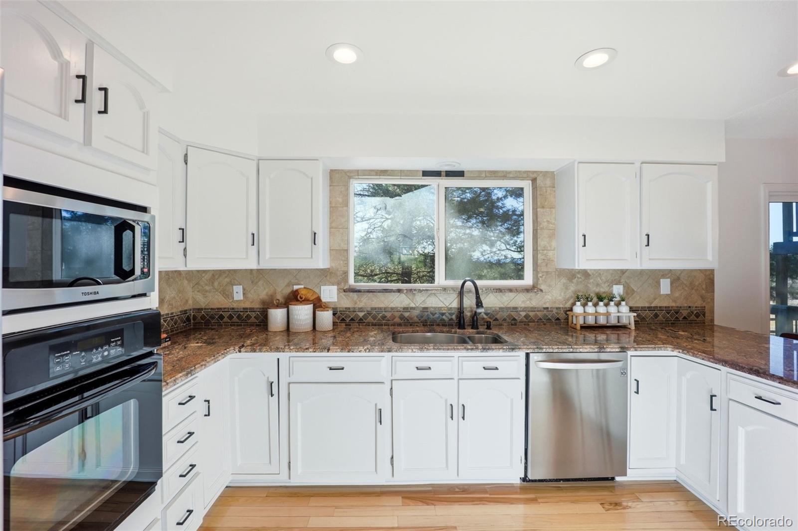 9212 East Tanglewood Road Franktown, CO 80116 - Photo 18 of 50 a kitchen with stainless steel appliances granite countertop a sink stove and cabinets