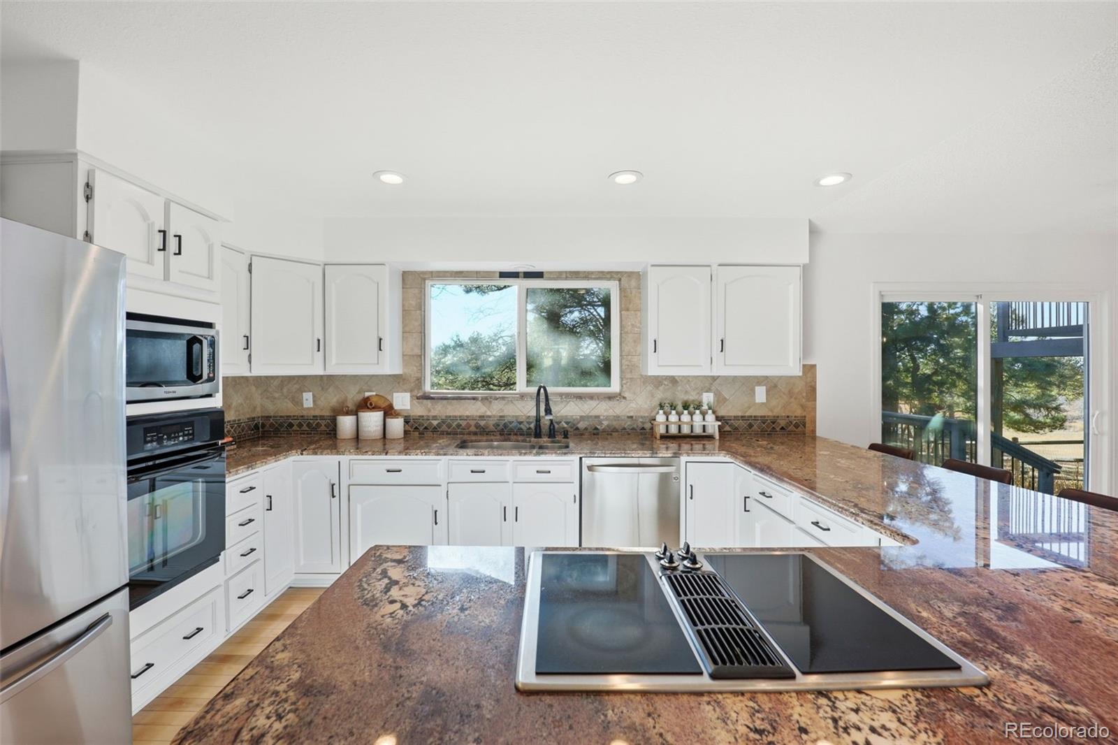 9212 East Tanglewood Road Franktown, CO 80116 - Photo 20 of 50 a kitchen with stainless steel appliances a sink a stove a microwave a sink and cabinets