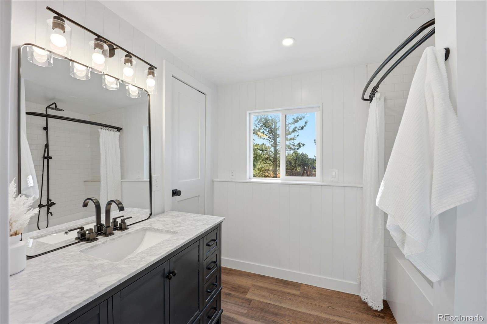 9212 East Tanglewood Road Franktown, CO 80116 - Photo 29 of 50 a bathroom with a granite countertop sink a mirror and a shower