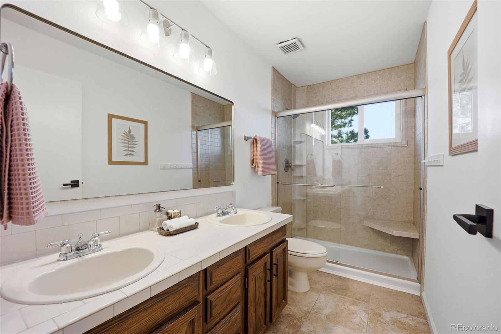 9212 East Tanglewood Road Franktown, CO 80116 - Photo 33 of 50 a bathroom with a granite countertop sink toilet and shower