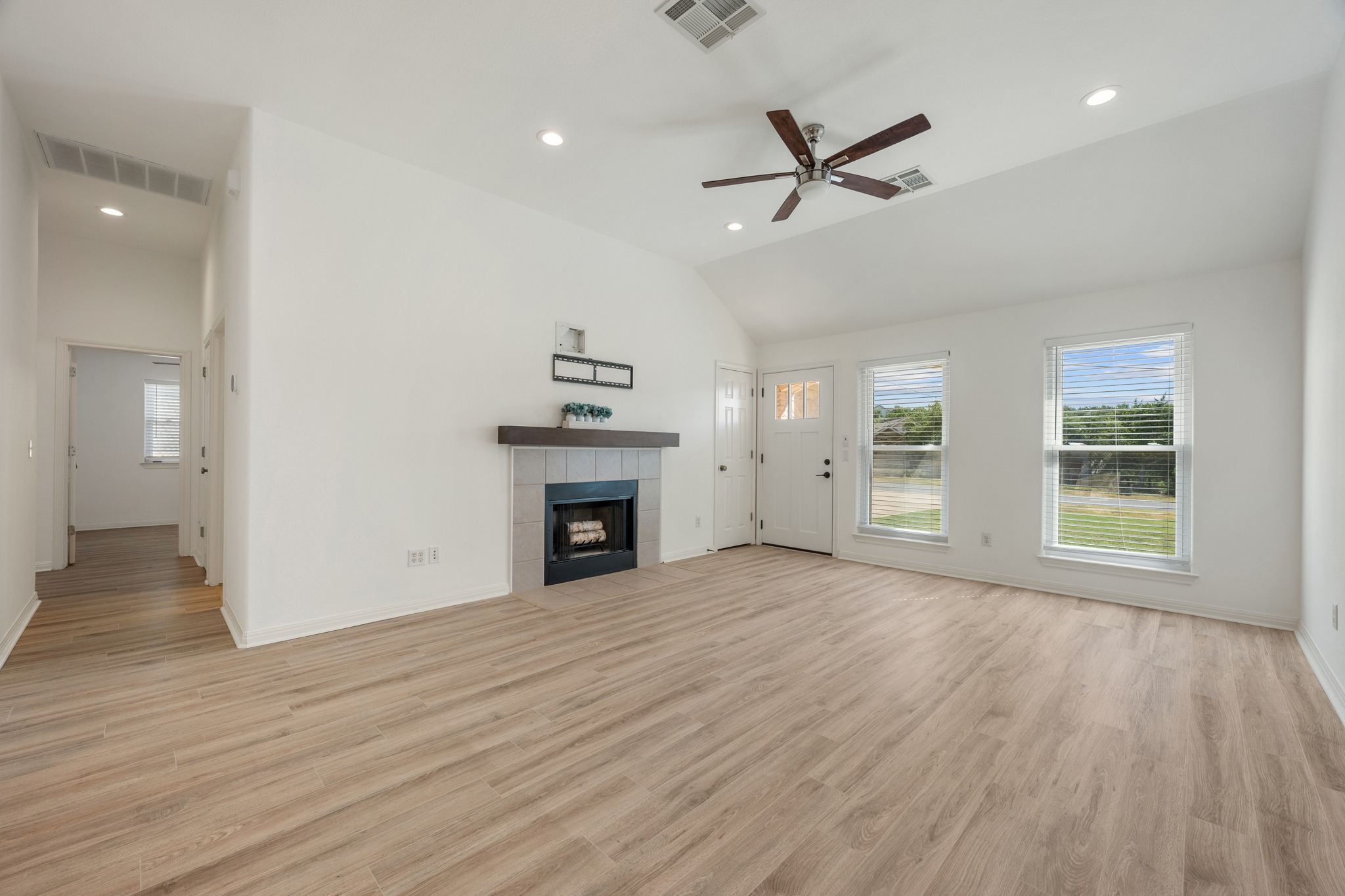 10114 Janet Loop Dripping Springs, TX 78620 - Photo 4 of 34 A spacious living room displays a tiled fireplace alongside smooth vinyl plank flooring.