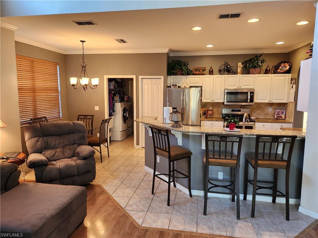 21524 Windham Run Estero, FL 33928 - Photo 6 of 18 a living room kitchen with stainless steel appliances kitchen island granite countertop furniture and a dining table