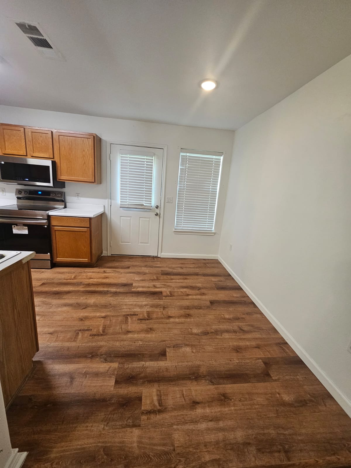 606 Trinity Street Lockhart, TX 78644 - Photo 5 of 23 A well-lit kitchen space featuring warm-toned wood flooring and convenient access to an outdoor area.